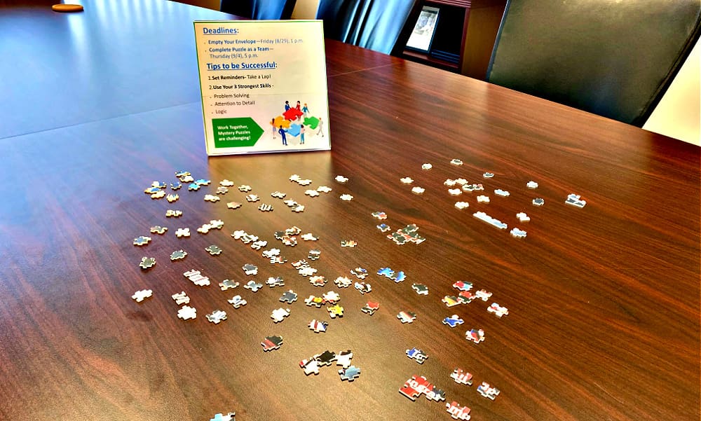 Wellness at Work Equals Energized Teams and Exceptional Service. Puzzle pieces coming together on conference room table.