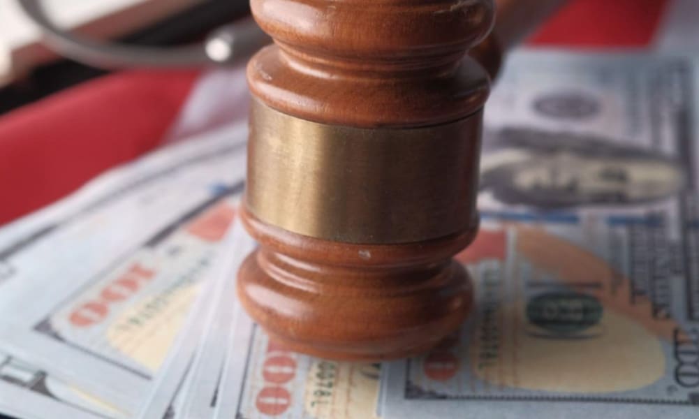 Wooden gavel slamming on a stack of money